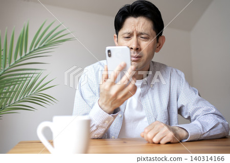 一位患有老花眼的中年男子,看不清智慧型手機螢幕。 一位患有老花眼的中年男子,看不清智慧型手機螢幕。 140314166