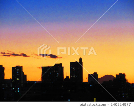 A landscape of the crimson sky at dusk, buildings, and the silhouette of Mount Fuji. A landscape of the crimson sky at dusk, buildings, and the silhouette of Mount Fuji. 140314977