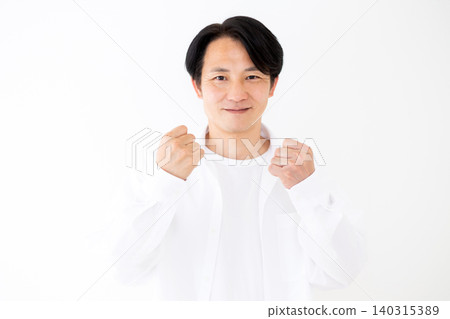 一位身穿白襯衫的中年男子在白色背景前擺出勝利姿勢的肖像。 一位身穿白襯衫的中年男子在白色背景前擺出勝利姿勢的肖像。 140315389