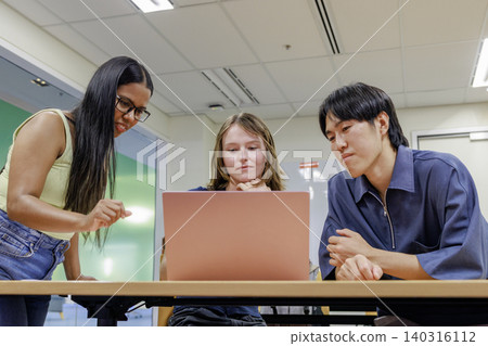 A university student smiling and studying with a foreign friend in a computer class. A university student smiling and studying with a foreign friend in a computer class. 140316112