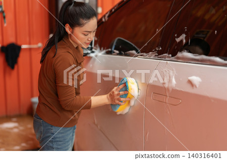 woman washing car with sponge and foam in a self-service car wash station 140316401