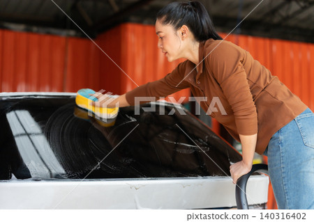 woman washing car with sponge and foam in a self-service car wash station woman washing car with sponge and foam in a self-service car wash station 140316402