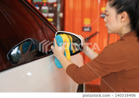 woman washing side mirror of car with sponge and foam in a self-service car wash station woman washing side mirror of car with sponge and foam in a self-service car wash station 140316406