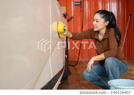 woman washing car with sponge and foam in a self-service car wash station woman washing car with sponge and foam in a self-service car wash station 140316407