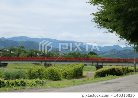 一座帶有紅色欄桿的橋樑橫跨宮川,遠處的山脈景色優美。 一座帶有紅色欄桿的橋樑橫跨宮川,遠處的山脈景色優美。 140316820