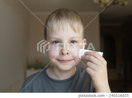 Cute 10 years old boy applying mineral sunscreen stick on his face. Caucasian child protecting freckled skin from sun damage with spf stick at home. Cute 10 years old boy applying mineral sunscreen stick on his face. Caucasian child protecting freckled skin from sun damage with spf stick at home. 140316835
