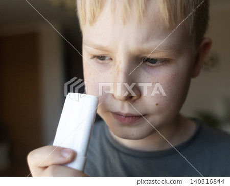 Cute 10 years old boy applying mineral sunscreen stick on his face. Caucasian child protecting freckled skin from sun damage with spf stick at home. Cute 10 years old boy applying mineral sunscreen stick on his face. Caucasian child protecting freckled skin from sun damage with spf stick at home. 140316844