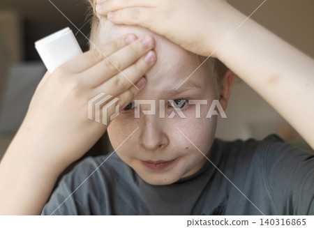 Cute 10 years old boy applying mineral sunscreen stick on his face. Caucasian child protecting freckled skin from sun damage with spf stick at home. Cute 10 years old boy applying mineral sunscreen stick on his face. Caucasian child protecting freckled skin from sun damage with spf stick at home. 140316865