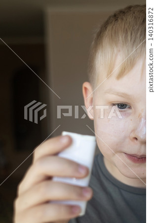 Cute 10 years old boy applying mineral sunscreen stick on his face. Caucasian child protecting freckled skin from sun damage with spf stick at home. 140316872