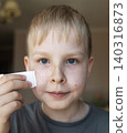 Cute 10 years old boy applying mineral sunscreen stick on his face. Caucasian child protecting freckled skin from sun damage with spf stick at home. Cute 10 years old boy applying mineral sunscreen stick on his face. Caucasian child protecting freckled skin from sun damage with spf stick at home. 140316873