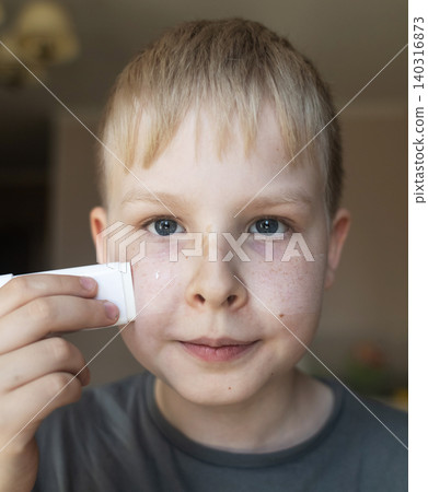 Cute 10 years old boy applying mineral sunscreen stick on his face. Caucasian child protecting freckled skin from sun damage with spf stick at home. Cute 10 years old boy applying mineral sunscreen stick on his face. Caucasian child protecting freckled skin from sun damage with spf stick at home. 140316873