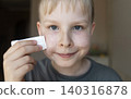 Cute 10 years old boy applying mineral sunscreen stick on his face. Caucasian child protecting freckled skin from sun damage with spf stick at home. Cute 10 years old boy applying mineral sunscreen stick on his face. Caucasian child protecting freckled skin from sun damage with spf stick at home. 140316878