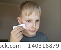 Cute 10 years old boy applying mineral sunscreen stick on his face. Caucasian child protecting freckled skin from sun damage with spf stick at home. Cute 10 years old boy applying mineral sunscreen stick on his face. Caucasian child protecting freckled skin from sun damage with spf stick at home. 140316879