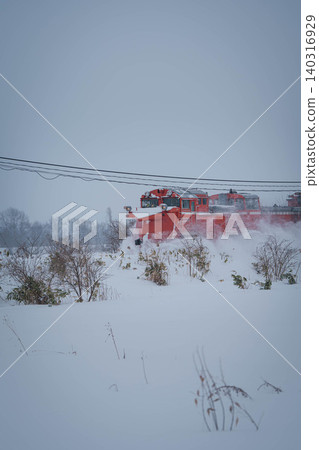 A red snowplow running through the snow A red snowplow running through the snow 140316929