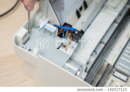Hand Using Screwdriver Repairing Inkjet Printer Interior With Exposed Wires And Cables Hand Using Screwdriver Repairing Inkjet Printer Interior With Exposed Wires And Cables 140317123