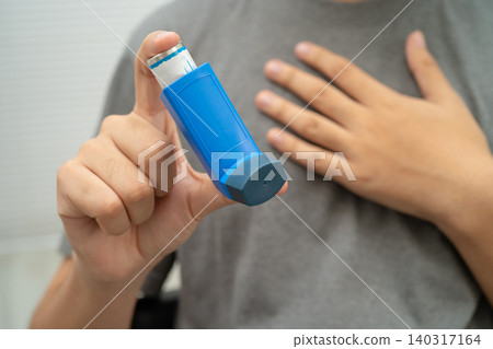 Asthma and chronic obstructive pulmonary disease COPD, Asian young man using metered dose inhaler MDI. Asthma and chronic obstructive pulmonary disease COPD, Asian young man using metered dose inhaler MDI. 140317164