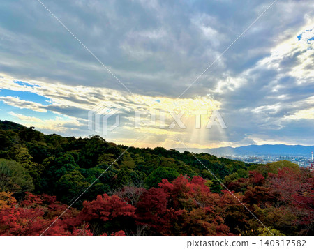 View from Kiyomizu-dera Temple in Kyoto: Light filtering through the clouds and a vibrant landscape of autumn leaves. View from Kiyomizu-dera Temple in Kyoto: Light filtering through the clouds and a vibrant landscape of autumn leaves. 140317582