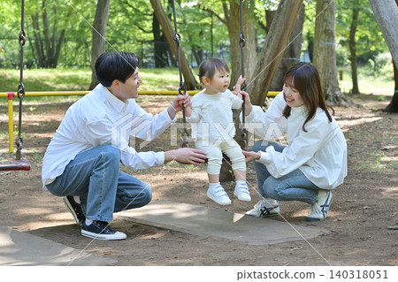 A family enjoying the swings in the park A family enjoying the swings in the park 140318051