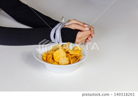Measuring tape bound hands reaching for chips Measuring tape bound hands reaching for chips 140318201