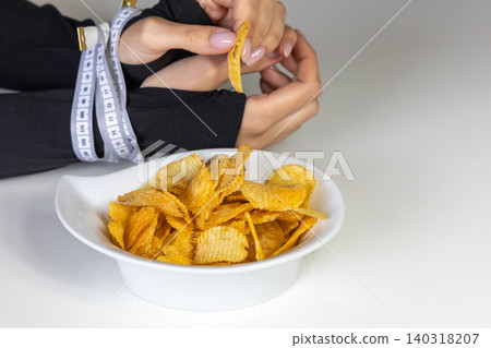 Measuring tape bound hands reaching for chips Measuring tape bound hands reaching for chips 140318207