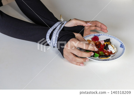 Measuring tape binding hands near sweet candy Measuring tape binding hands near sweet candy 140318209