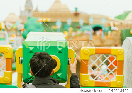 kid looks through a telescope in playground kid looks through a telescope in playground 140318453