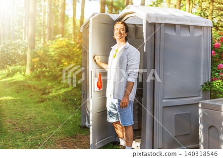 Relieved man smiling as he exits an outdoor portable toilet after overcoming gastrointestinal problems, diarrhea, or an upset stomach. Relieved man smiling as he exits an outdoor portable toilet after overcoming gastrointestinal problems, diarrhea, or an upset stomach. 140318546