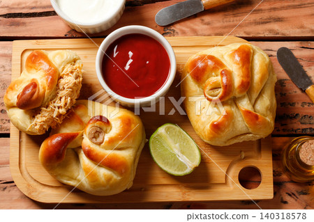 Traditional baked savory closed esfihas filled with chicken, olives, lemon, and ketchup sauce, displayed on a cutting board from above. Traditional baked savory closed esfihas filled with chicken, olives, lemon, and ketchup sauce, displayed on a cutting board from above. 140318578