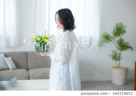 一位年輕女子在客廳拿著花瓶 一位年輕女子在客廳拿著花瓶 140319852