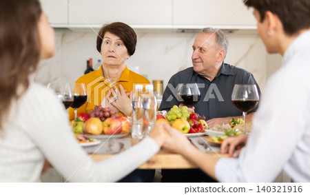 Happy family having dinner together at festive table at home Happy family having dinner together at festive table at home 140321916