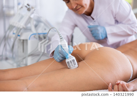 Aesthetician performing cryotherapy using cooling attachment on female buttocks Aesthetician performing cryotherapy using cooling attachment on female buttocks 140321990