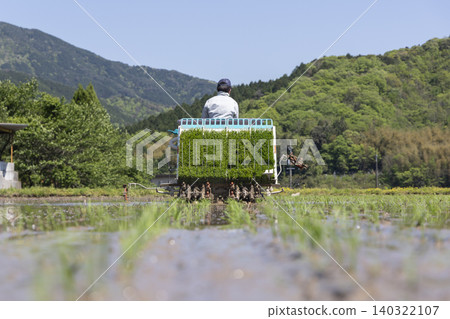 一位農民正在農村稻田裡用插秧機插秧。 一位農民正在農村稻田裡用插秧機插秧。 140322107