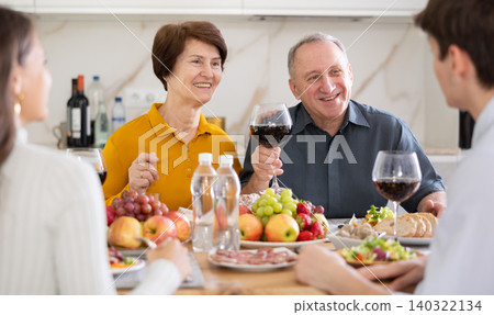 Senior man and woman enjoying family dinner with youth 140322134