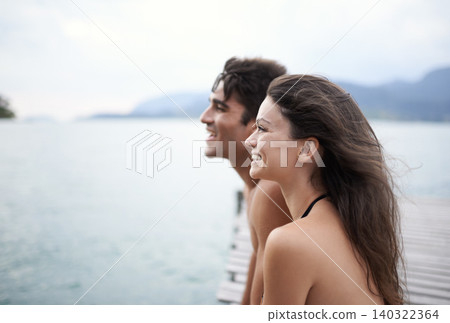 Couple, jetty and travel to ocean on adventure, love and relax by water on summer holiday. People, swimwear and bonding for relationship in outdoor, support and smile on weekend trip to sea or nature 140322364