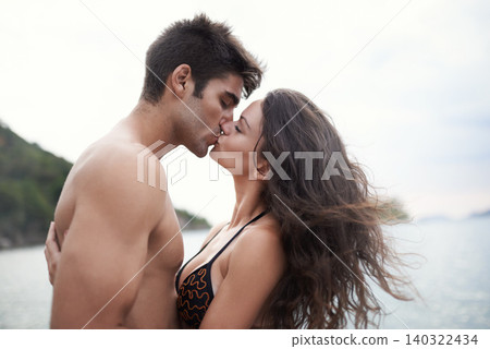 Couple, kiss and travel to ocean on vacation, romance and relax by water on summer holiday. People, swimwear and bonding for relationship in outdoor, support and love on weekend trip to sea or nature Couple, kiss and travel to ocean on vacation, romance and relax by water on summer holiday. People, swimwear and bonding for relationship in outdoor, support and love on weekend trip to sea or nature 140322434