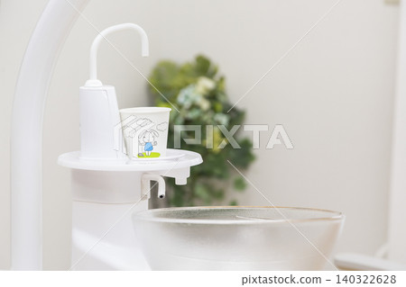 Close-up of a dental spittoon and a rabbit-patterned cup. Close-up of a dental spittoon and a rabbit-patterned cup. 140322628