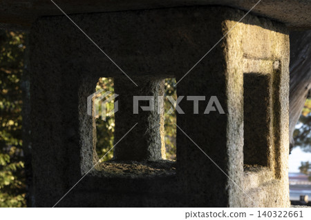 A close-up of the light shining into the firebox of a stone lantern at a shrine. A close-up of the light shining into the firebox of a stone lantern at a shrine. 140322661
