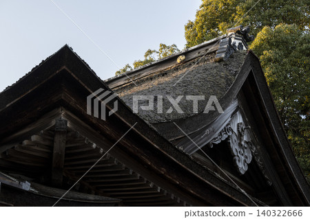 A composition showing a thatched-roof shrine viewed from an elevated angle. A composition showing a thatched-roof shrine viewed from an elevated angle. 140322666