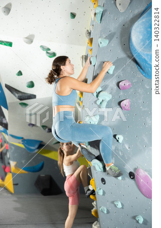 Girl in sportswear practicing rock climbing on climbing wall Girl in sportswear practicing rock climbing on climbing wall 140322814