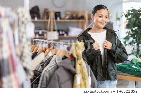 Modern asian woman choosing and trying stylish-looking leather jacket in clothing shop Modern asian woman choosing and trying stylish-looking leather jacket in clothing shop 140322852