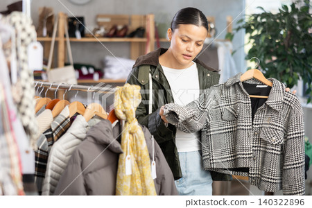 Adult woman chooses coat in clothing store Adult woman chooses coat in clothing store 140322896