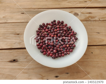 Fresh phalsa berries on white plate with wooden table Fresh phalsa berries on white plate with wooden table 140322970