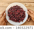 Hand holding plate filled with fresh phalsa seasonal fruit of Pakistan 140322971