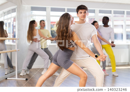 Young man and woman practicing tango dance in pair in training hall Young man and woman practicing tango dance in pair in training hall 140323246
