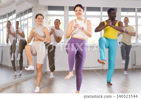 Young Asian woman practicing vigorous zumba with group Young Asian woman practicing vigorous zumba with group 140323544