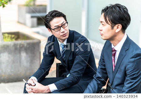三位身著西裝的日本商人正在戶外聊天。 三位身著西裝的日本商人正在戶外聊天。 140323934
