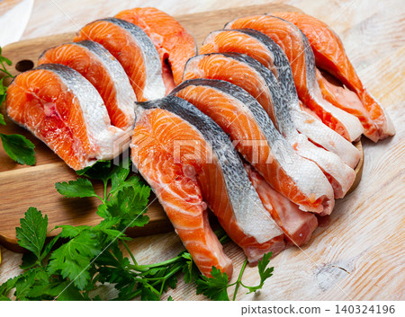 Raw steaks of salmon with seasonings on wooden background Raw steaks of salmon with seasonings on wooden background 140324196