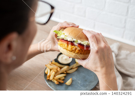 Woman holding crispy chicken burger Woman holding crispy chicken burger 140324291