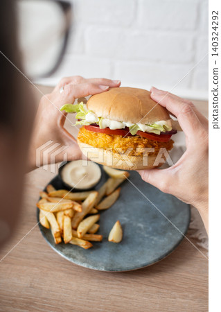 Woman holding crispy chicken burger Woman holding crispy chicken burger 140324292