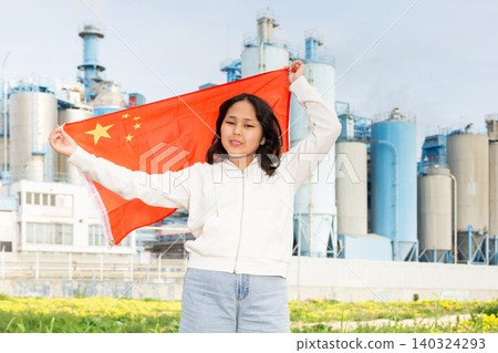 Happy young woman with flag of China against background of factory Happy young woman with flag of China against background of factory 140324293